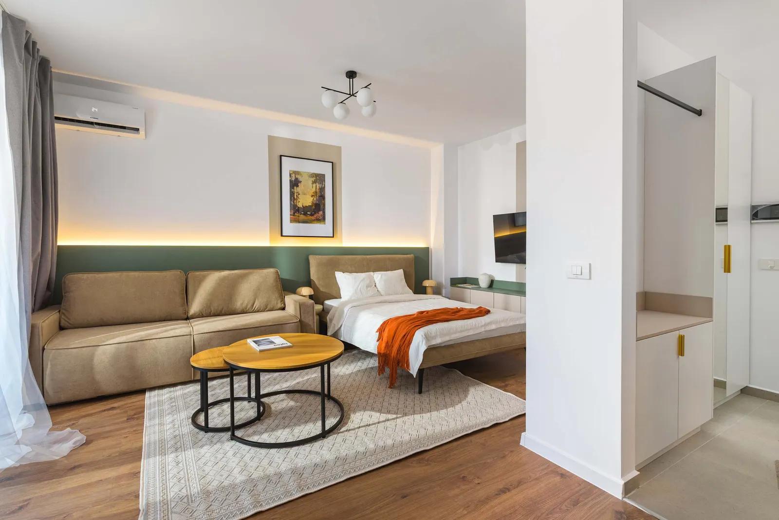 Bright studio with a beige sofa, round coffee tables and the bed behind, at City of Mara, Timișoara