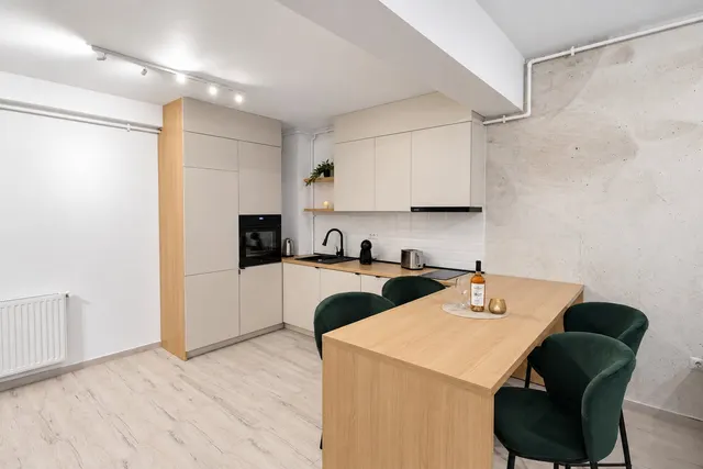 Fully equipped kitchen with a wooden table and green chairs, at Casa del Mar, Mamaia Nord