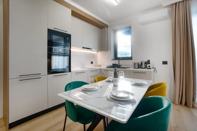 White kitchen with a built-in oven and a table for four, at Coresi, Brașov