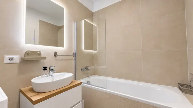 Bathroom with a bathtub, a backlit mirror and a wooden-topped vanity, at Torontal, Timișoara
