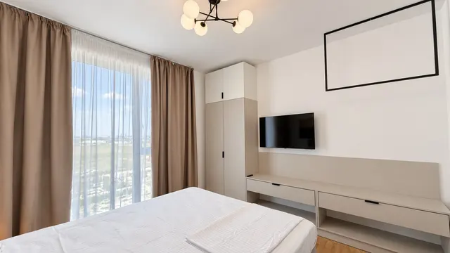 Bright bedroom with a large window and an upholstered bench, at Torontal, Timișoara
