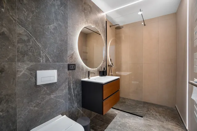 Bathroom with a walk-in shower, grey marble and a round backlit mirror, at Coresi, Brașov