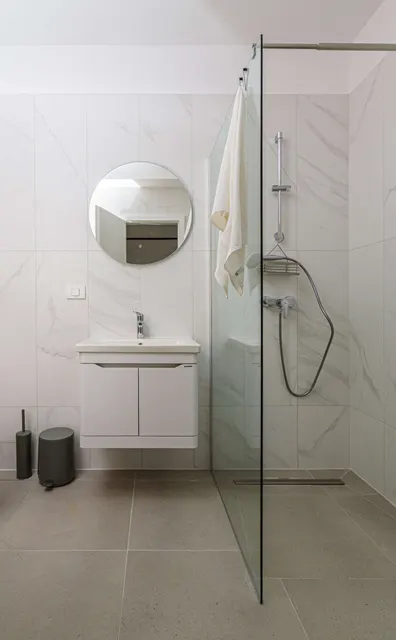 Bathroom with a walk-in shower and a round mirror, at City of Mara, Timișoara