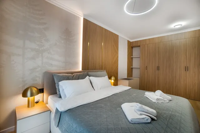 Bedroom with wooden wardrobes and gold bedside lamps, at Coresi, Brașov