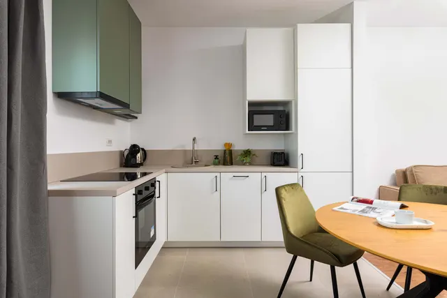 White kitchen with a built-in oven and a green hood, at City of Mara, Timișoara