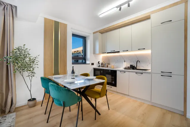 Kitchen with a marble table and green and yellow chairs, at Coresi, Brașov