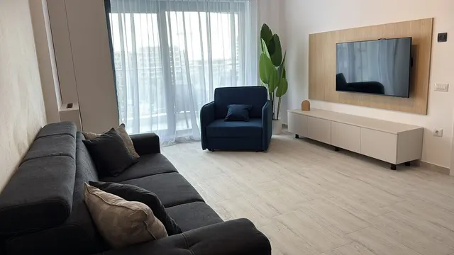 Living room with a blue armchair, a sofa and a door onto the balcony, at Casa del Mar, Mamaia Nord