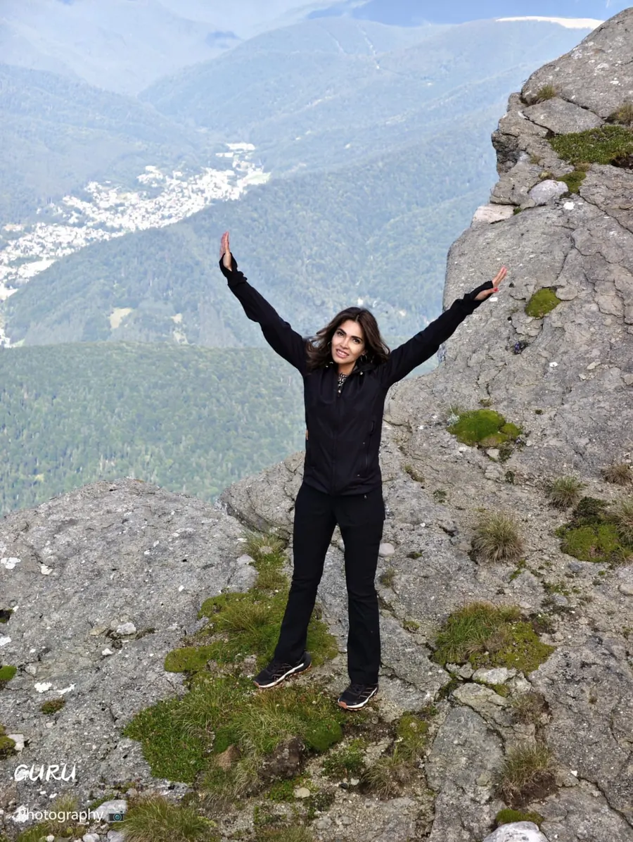 Alina Tomșa on a rock in the mountains, arms raised